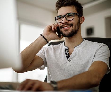 Man talking on phone while using computer